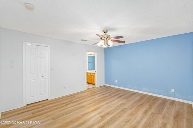 spare room with a textured ceiling, light hardwood / wood-style flooring, and ceiling fan