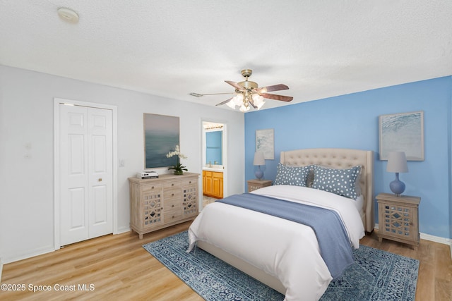 bedroom with ceiling fan, hardwood / wood-style floors, connected bathroom, a textured ceiling, and a closet