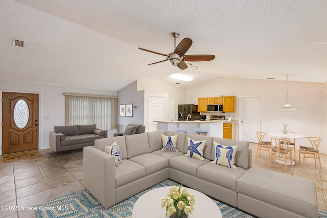 living room featuring lofted ceiling, light tile patterned floors, a textured ceiling, and ceiling fan