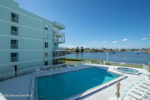 view of swimming pool with a hot tub, a patio, and a water view