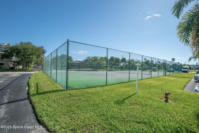 view of tennis court featuring a lawn