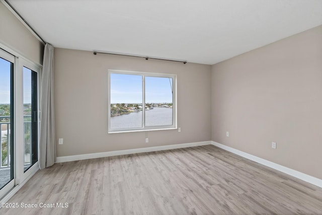 unfurnished room featuring light hardwood / wood-style floors and a water view