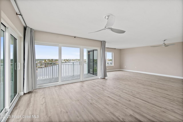 empty room featuring light hardwood / wood-style floors, ceiling fan, and a water view