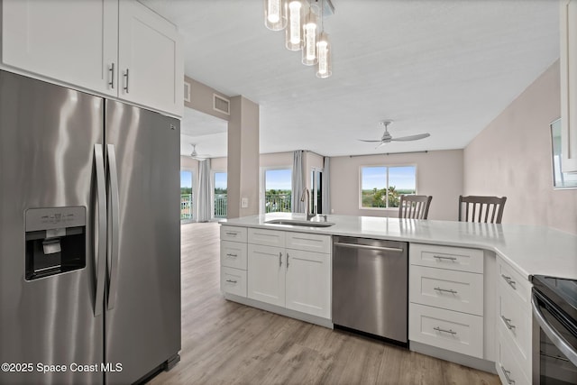 kitchen featuring sink, light wood-type flooring, white cabinets, and appliances with stainless steel finishes