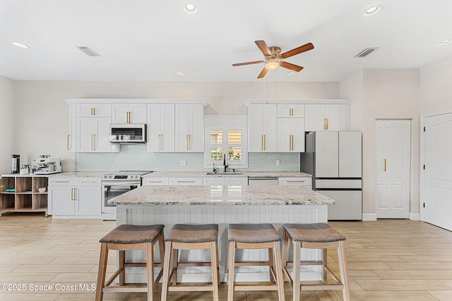 kitchen with white cabinets, a center island, stainless steel range with electric stovetop, and white fridge