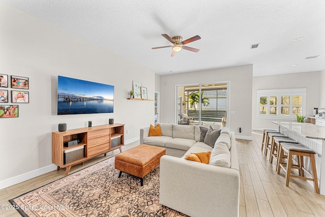 living room featuring a textured ceiling, ceiling fan, and light hardwood / wood-style flooring