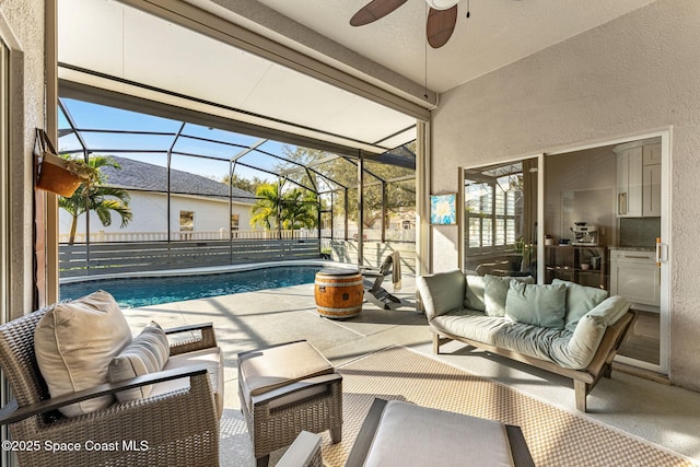 view of patio with ceiling fan, glass enclosure, and an outdoor living space with a fire pit