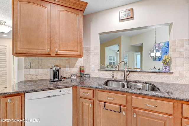 kitchen featuring sink, dishwasher, dark stone countertops, decorative backsplash, and decorative light fixtures