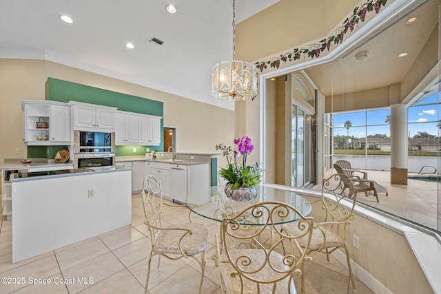 kitchen with pendant lighting, built in microwave, white cabinetry, dishwasher, and sink