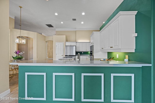 kitchen featuring white cabinetry, stainless steel appliances, a notable chandelier, decorative light fixtures, and kitchen peninsula