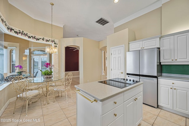 kitchen with light tile patterned flooring, white cabinetry, hanging light fixtures, stainless steel fridge, and black electric stovetop