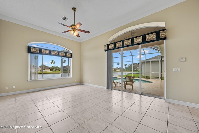 tiled spare room featuring a water view, ceiling fan, crown molding, and a wealth of natural light