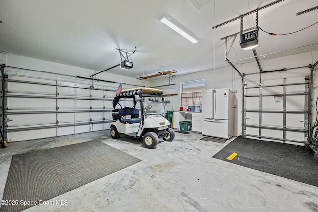 garage with a garage door opener and white refrigerator