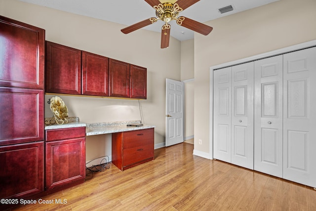 unfurnished office featuring ceiling fan, a baseboard radiator, built in desk, and light wood-type flooring