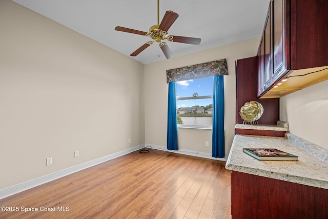 kitchen with light stone countertops, ceiling fan, and light hardwood / wood-style flooring