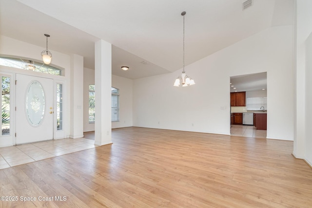 entrance foyer featuring a notable chandelier, plenty of natural light, light hardwood / wood-style floors, and high vaulted ceiling