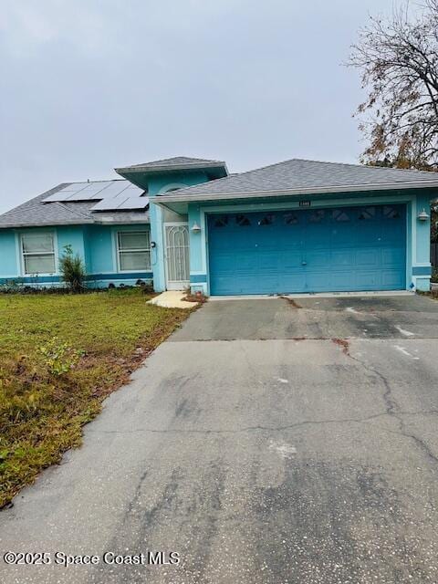 view of front of home featuring a garage, a front yard, and solar panels