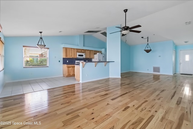 unfurnished living room with high vaulted ceiling, light hardwood / wood-style floors, and ceiling fan