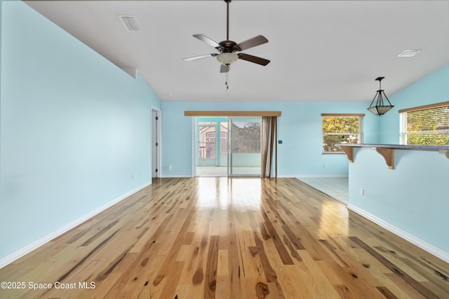 unfurnished living room with vaulted ceiling, ceiling fan, plenty of natural light, and light hardwood / wood-style floors