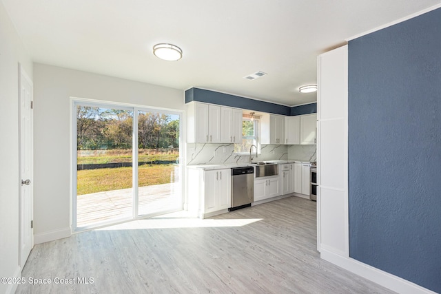 kitchen with stainless steel dishwasher, backsplash, light wood-type flooring, and white cabinetry