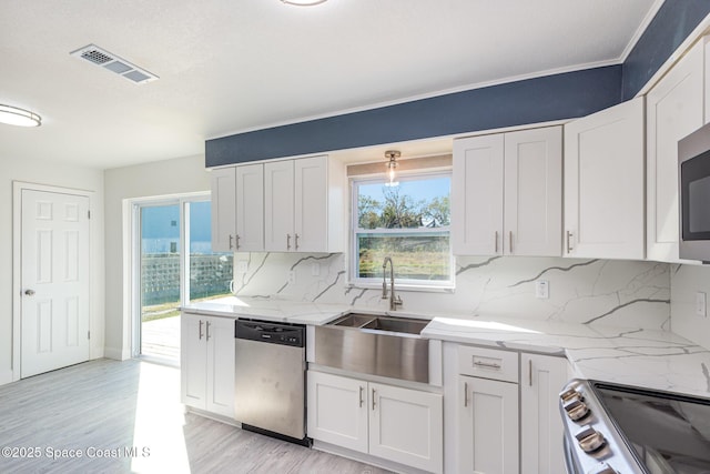 kitchen featuring plenty of natural light, white cabinets, stainless steel appliances, and tasteful backsplash