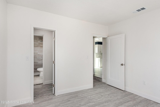 unfurnished bedroom featuring light wood-type flooring and connected bathroom