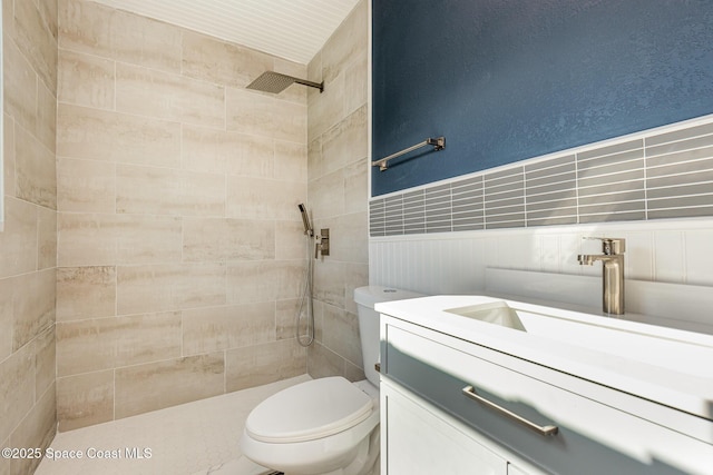 bathroom with tiled shower, vanity, and toilet