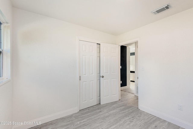 unfurnished bedroom with a closet and light hardwood / wood-style floors