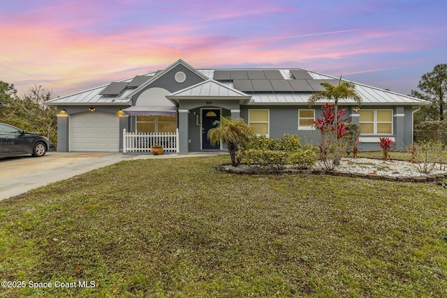 view of front of property featuring a garage, a lawn, and solar panels