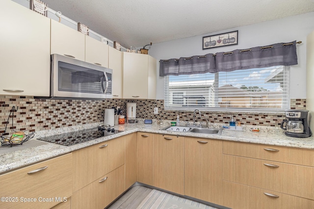 kitchen with a textured ceiling, black electric stovetop, decorative backsplash, sink, and light stone counters