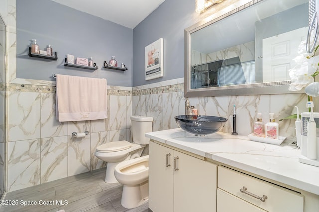 bathroom featuring vanity, tile walls, toilet, walk in shower, and a bidet