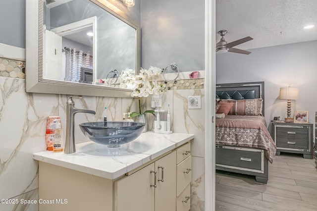 bathroom featuring wood-type flooring, ceiling fan, a textured ceiling, vanity, and decorative backsplash