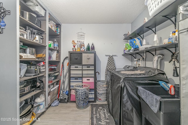 laundry area with washing machine and dryer, a textured ceiling, and light hardwood / wood-style flooring