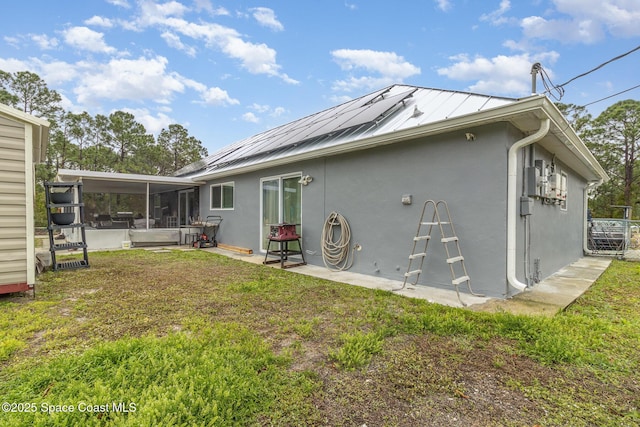 back of property featuring a yard, a sunroom, and solar panels