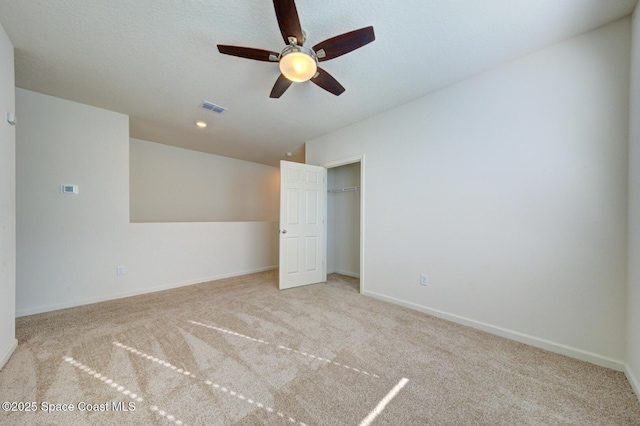 unfurnished bedroom with light colored carpet, a textured ceiling, ceiling fan, and a closet