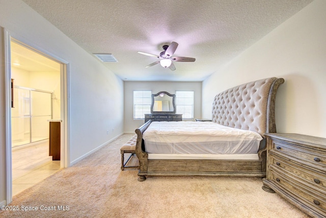 bedroom featuring ceiling fan, light colored carpet, connected bathroom, and a textured ceiling