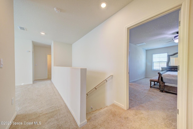 corridor with light colored carpet and a textured ceiling