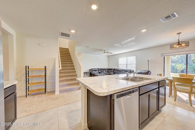 kitchen featuring dishwasher, pendant lighting, a kitchen island with sink, and light carpet