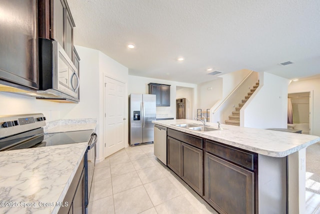 kitchen with a kitchen island with sink, sink, dark brown cabinetry, and appliances with stainless steel finishes