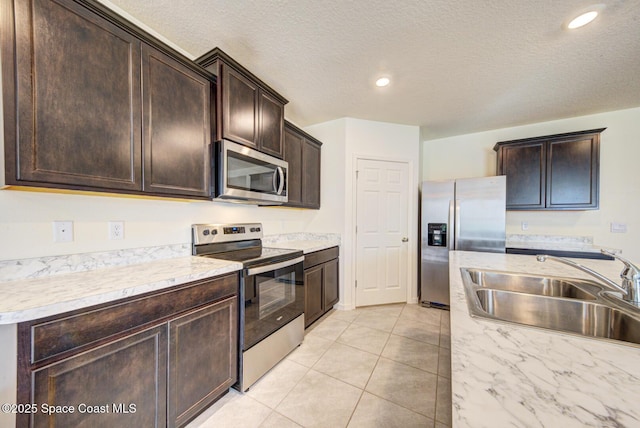 kitchen featuring sink, appliances with stainless steel finishes, dark brown cabinets, a textured ceiling, and light tile patterned flooring