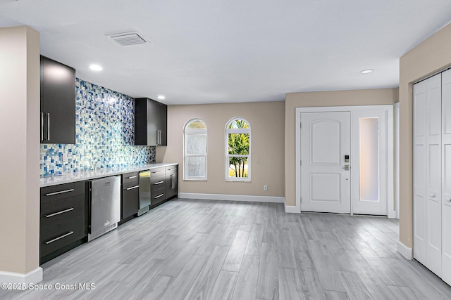 kitchen featuring stainless steel dishwasher, light hardwood / wood-style floors, and decorative backsplash