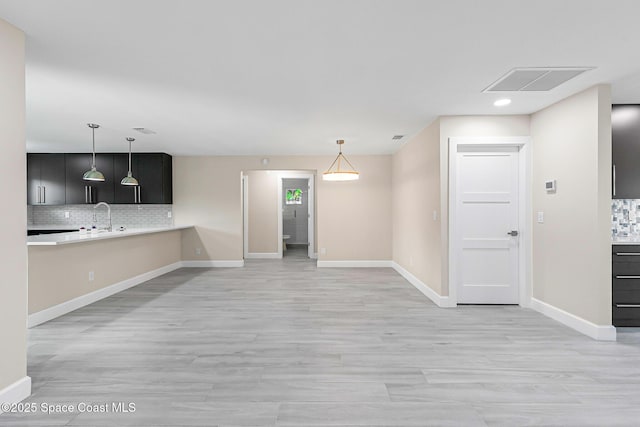 kitchen featuring tasteful backsplash, kitchen peninsula, light hardwood / wood-style flooring, and pendant lighting