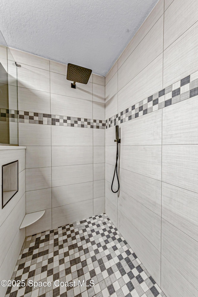 bathroom featuring a textured ceiling and a tile shower