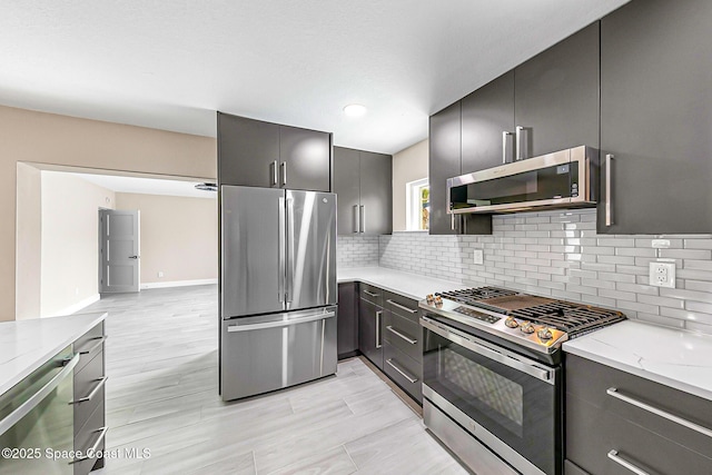 kitchen with light stone countertops, appliances with stainless steel finishes, and backsplash