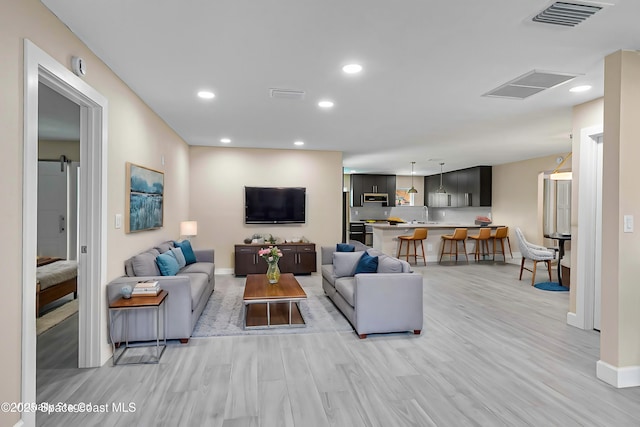 living room with a barn door and light wood-type flooring