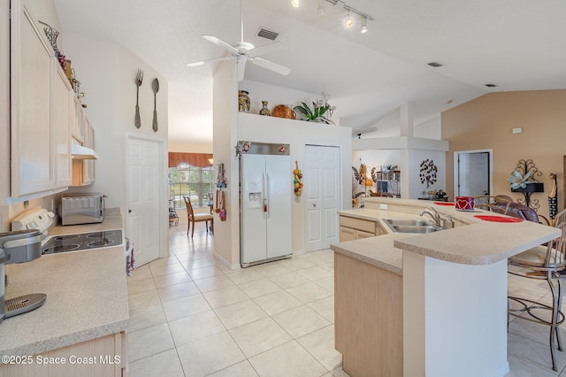 kitchen featuring white fridge with ice dispenser, light brown cabinetry, a kitchen breakfast bar, sink, and light tile patterned floors