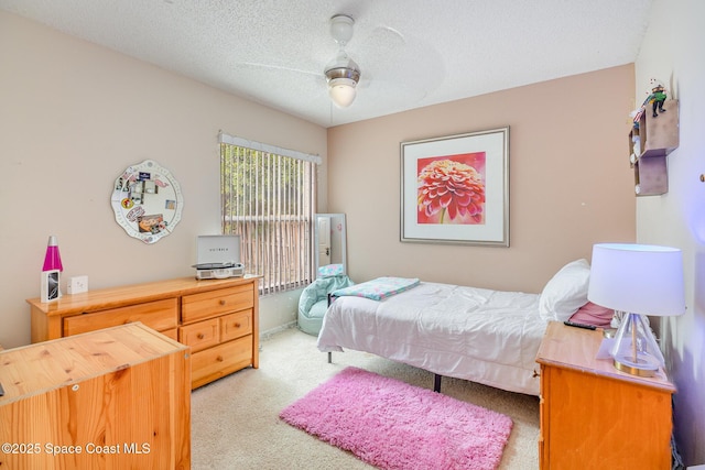 bedroom with ceiling fan, light colored carpet, and a textured ceiling