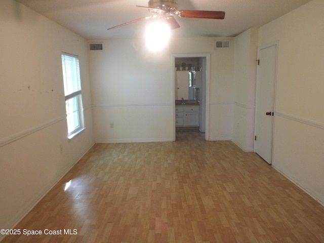 empty room featuring ceiling fan, sink, and light hardwood / wood-style flooring