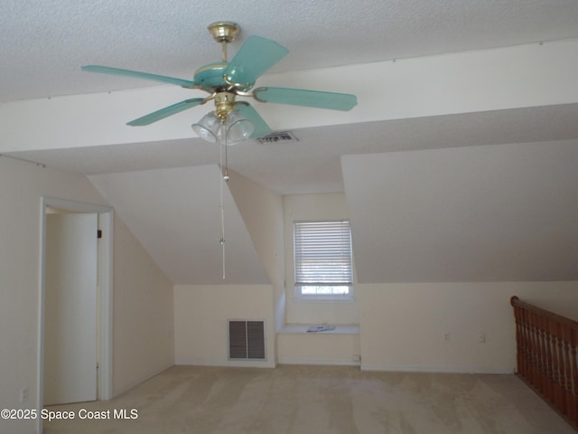 additional living space with light colored carpet, a textured ceiling, vaulted ceiling, and ceiling fan