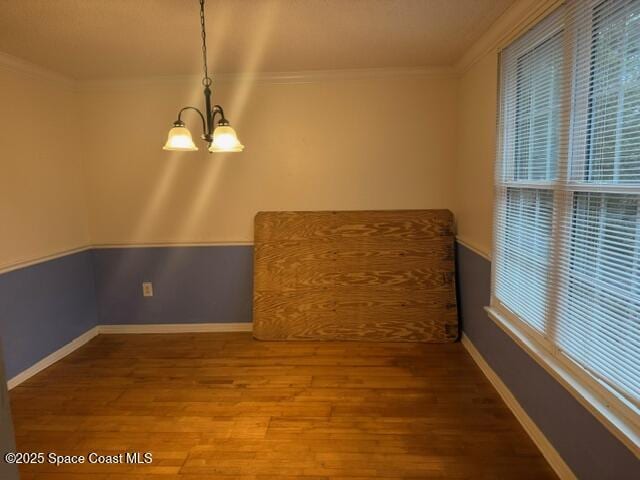 unfurnished room with hardwood / wood-style flooring, a chandelier, and ornamental molding